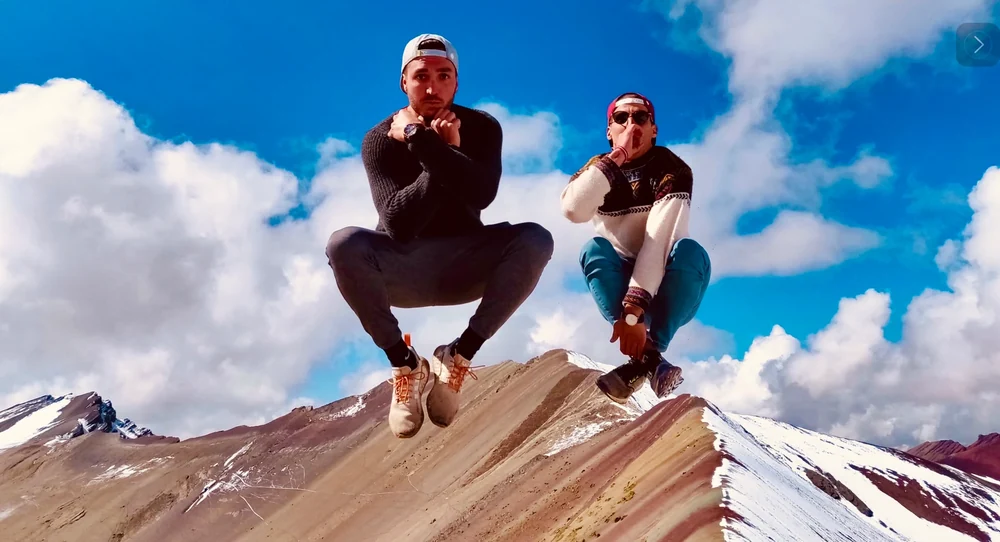Nuri and a friend leaping above a mountain landscape